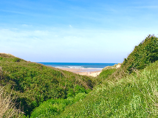 View to Croyde Beach with surf from the village footpath